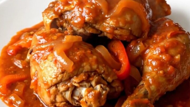 A steaming plate of slow-cooked Basque chicken with peppers and onions.