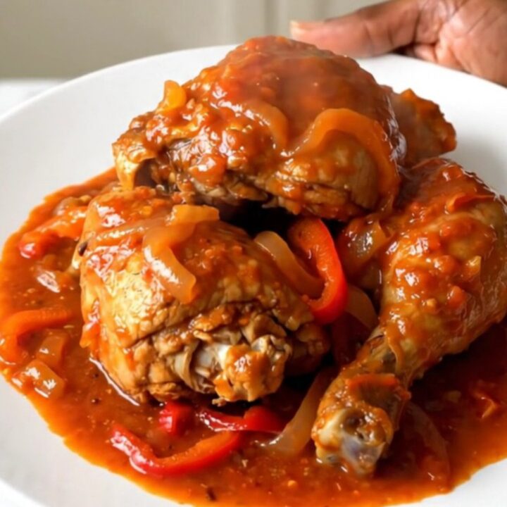 A steaming plate of slow-cooked Basque chicken with peppers and onions.