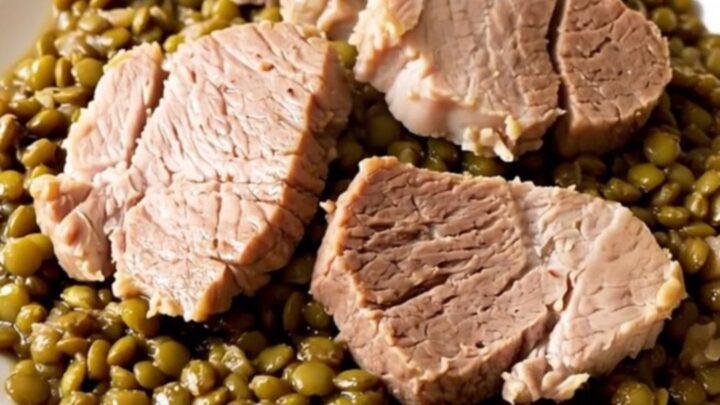 A rustic slow cooker filled with salted pork, lentils, and carrots in a bright kitchen setting.