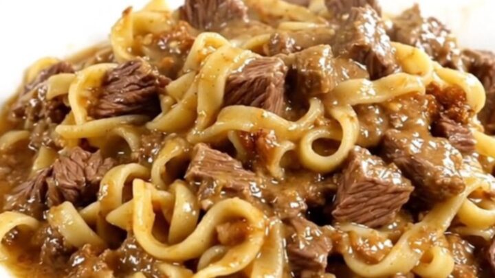 A steaming, creamy beef and egg noodle casserole served on a white plate.