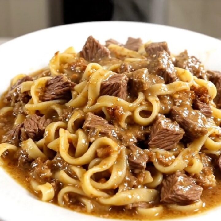 A steaming, creamy beef and egg noodle casserole served on a white plate.