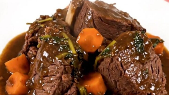 A top-down view of raw beef and carrots being added to a black slow cooker on a white quartz countertop.