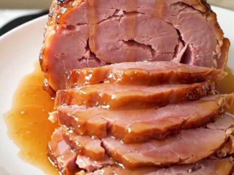 A glossy, glazed spiral-cut ham sitting in a slow cooker on a bright kitchen counter.