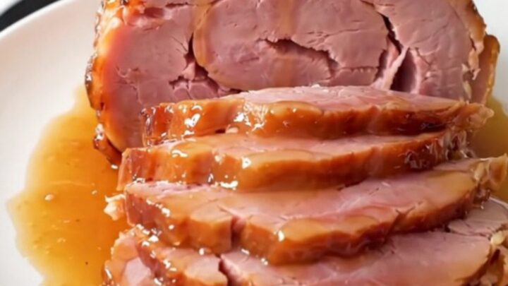 A glossy, glazed spiral-cut ham sitting in a slow cooker on a bright kitchen counter.
