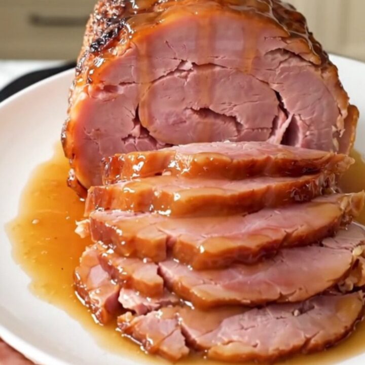 A glossy, glazed spiral-cut ham sitting in a slow cooker on a bright kitchen counter.
