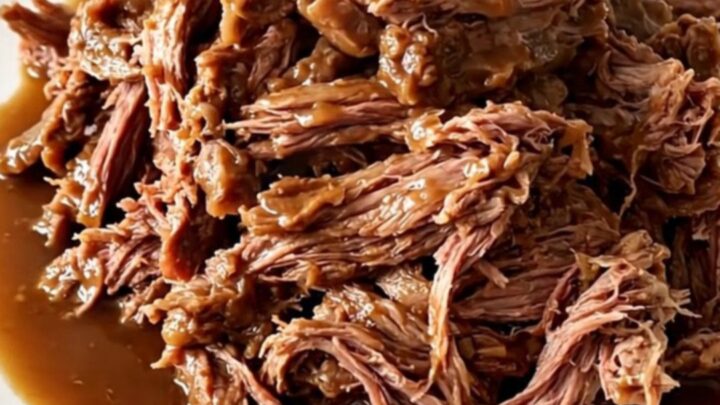 A succulent, shredded slow-cooked leg of lamb with soft carrots on a white plate.