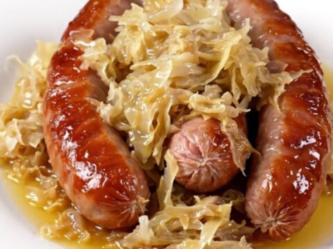 A rustic bowl of choucroute garnie featuring tender smoked pork, sauerkraut, and steamed potatoes.