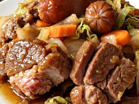 A rustic slow cooker Potée Auvergnate served in a white bowl with tender pork, carrots, and cabbage.