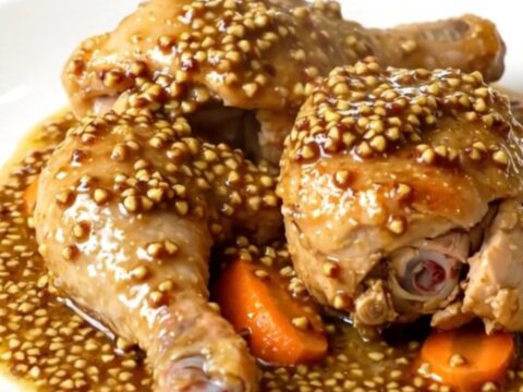 A slow cooker filled with golden chicken legs, carrots, and a creamy mustard sauce, ready to be served.