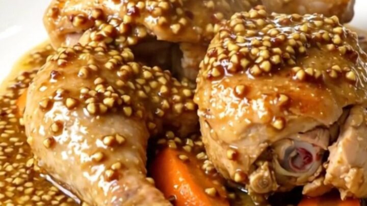 A slow cooker filled with golden chicken legs, carrots, and a creamy mustard sauce, ready to be served.