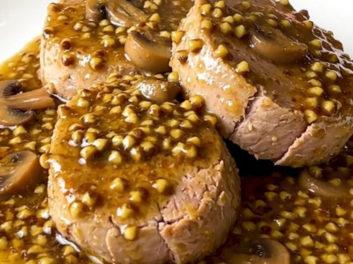 A slow cooker filled with raw pork tenderloin, sliced mushrooms, and creamy mustard sauce.