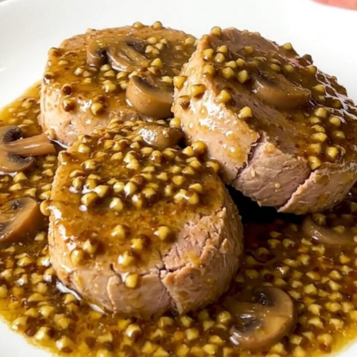 A slow cooker filled with raw pork tenderloin, sliced mushrooms, and creamy mustard sauce.