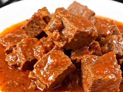 A close-up of a slow-cooker Provençal pork stew served on a white plate with visible chunks of tender pork and peppers.