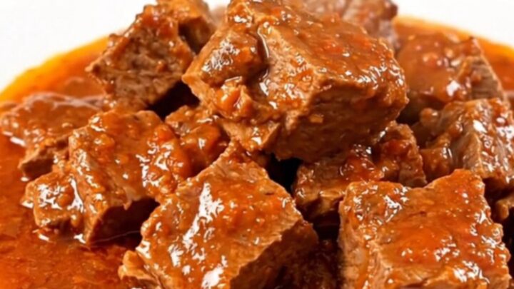 A close-up of a slow-cooker Provençal pork stew served on a white plate with visible chunks of tender pork and peppers.