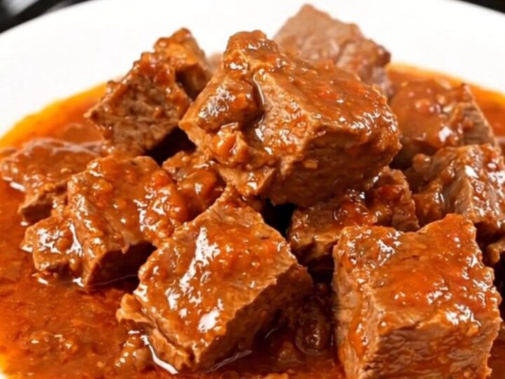 A close-up of a slow-cooker Provençal pork stew served on a white plate with visible chunks of tender pork and peppers.