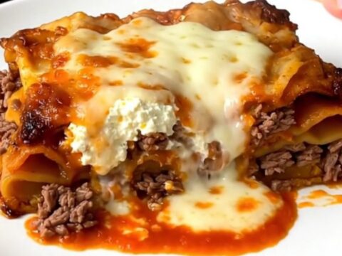 A steaming, golden slice of slow cooker beef lasagna on a white plate.