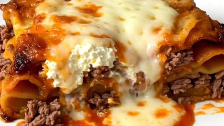 A steaming, golden slice of slow cooker beef lasagna on a white plate.