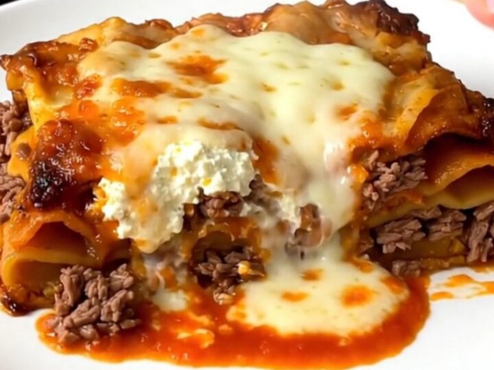 A steaming, golden slice of slow cooker beef lasagna on a white plate.