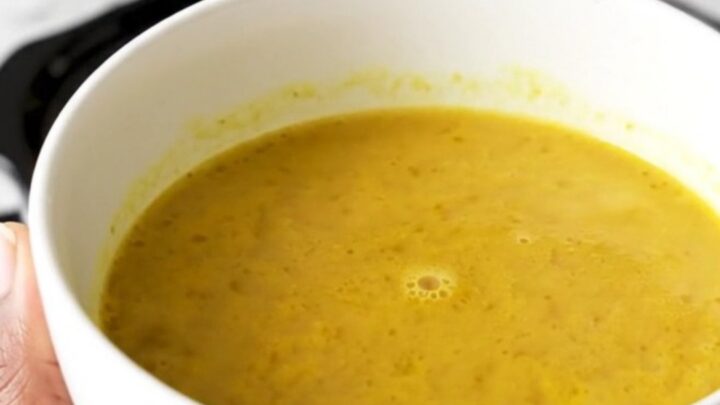 A bowl of golden, velvety butternut squash coconut curry soup in a white bowl.