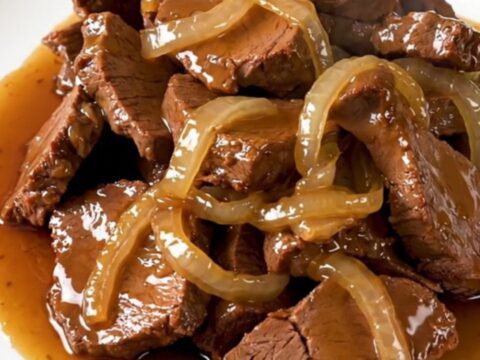 Slow-cooked veal tendrons with caramelized onions in a rich honey soy sauce on a white plate.