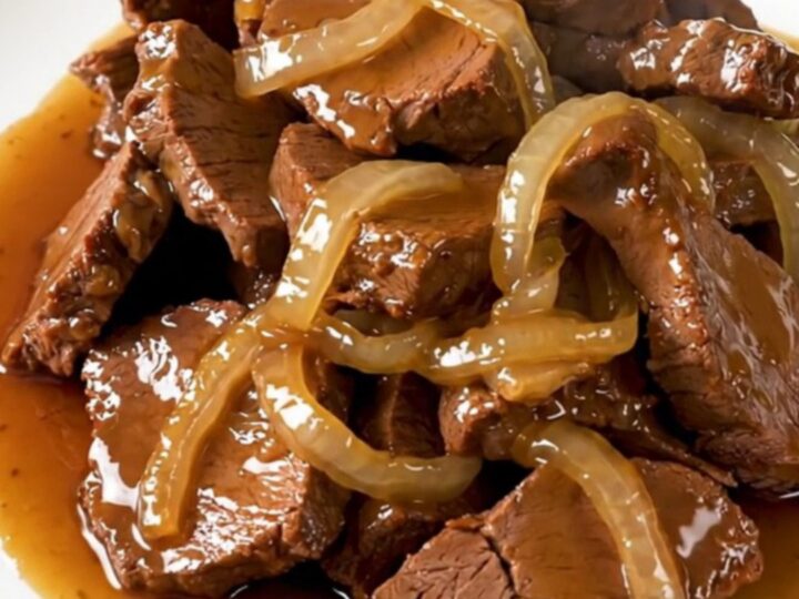 Slow-cooked veal tendrons with caramelized onions in a rich honey soy sauce on a white plate.