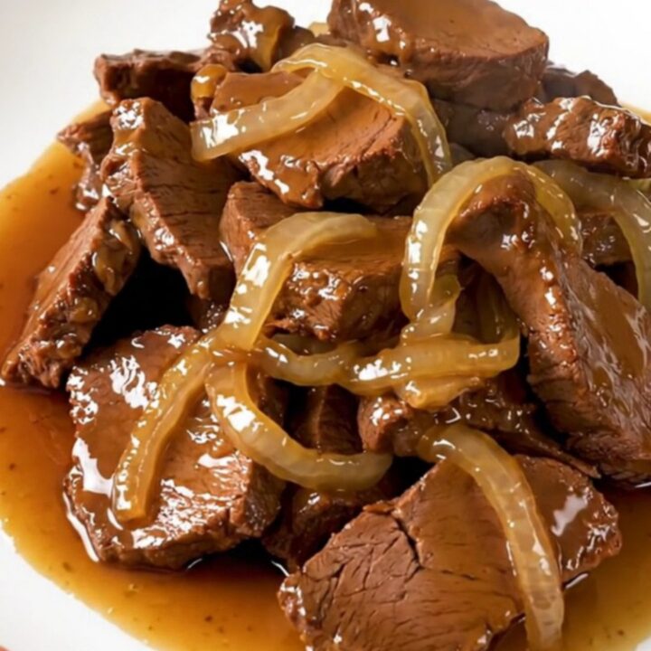 Slow-cooked veal tendrons with caramelized onions in a rich honey soy sauce on a white plate.