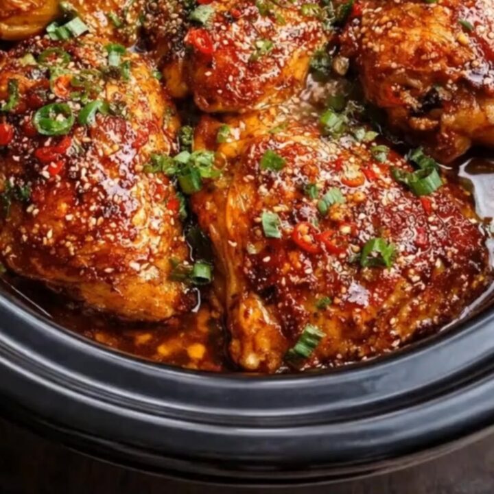 A slow push-in shot of tender honey garlic chili chicken thighs garnished with sesame seeds and green onions in a slow