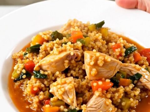 A slow cooker filled with chicken thighs, carrots, turnips, and chickpeas in a rich, glossy tomato-based sauce.