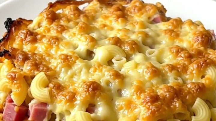 A top-down view into a black slow cooker filled with a creamy, golden-brown ham and macaroni gratin.