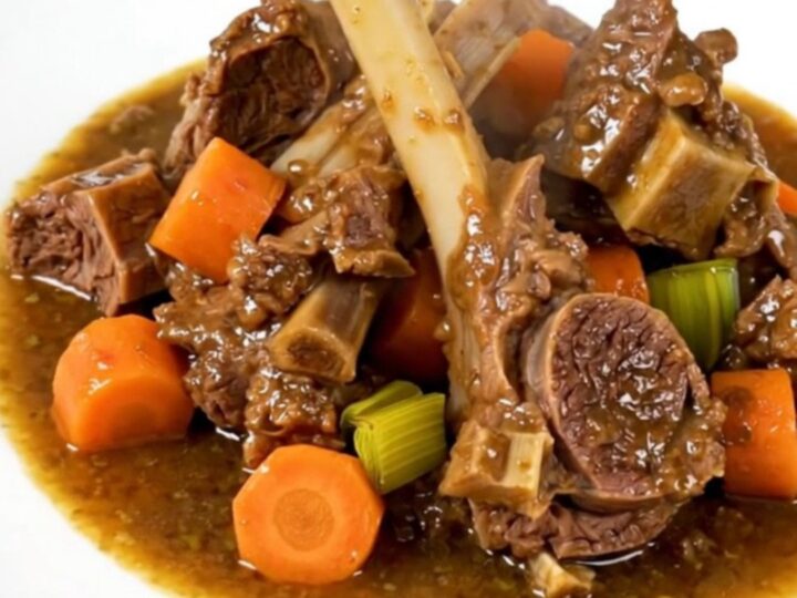 A steaming, glossy lamb stew served in a white bowl on a bright kitchen counter.