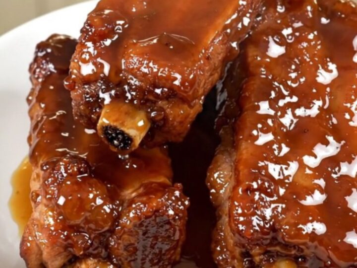 A plate of sticky, glazed slow-cooked pork ribs with a deep brown honey-soy coating.