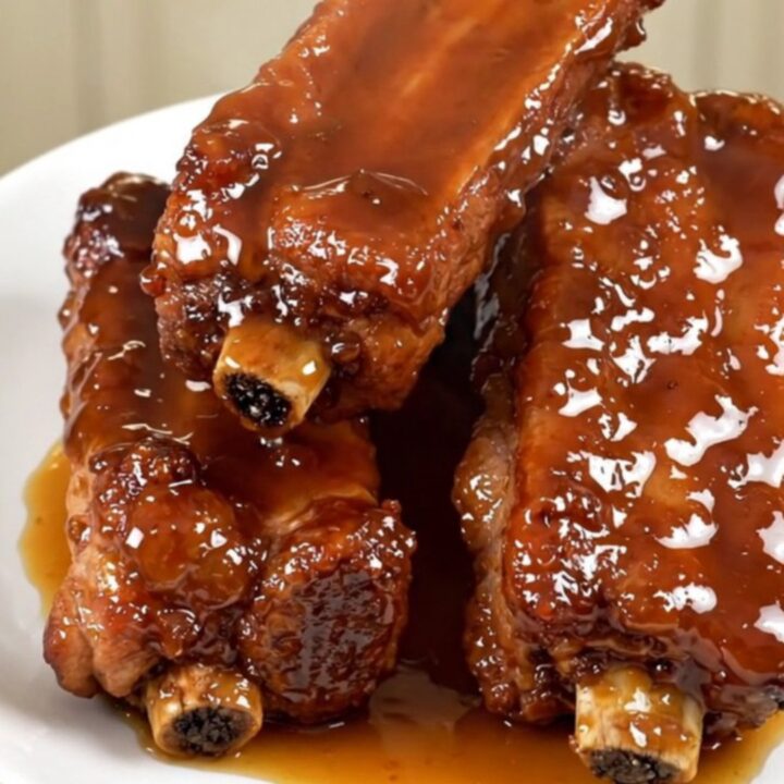 A plate of sticky, glazed slow-cooked pork ribs with a deep brown honey-soy coating.