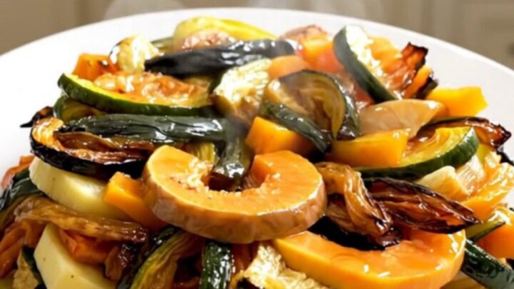 A top-down view of raw sliced butternut squash, potatoes, and onions layered in a black slow cooker insert.