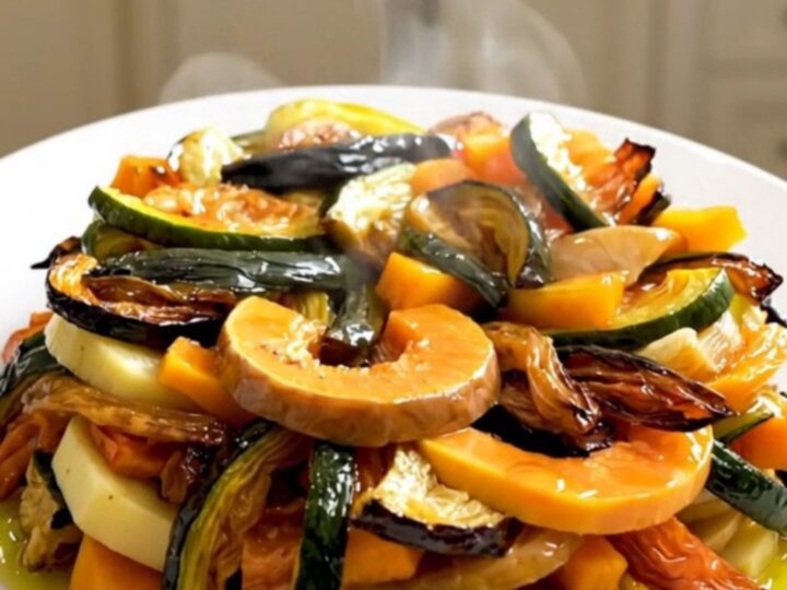 A top-down view of raw sliced butternut squash, potatoes, and onions layered in a black slow cooker insert.