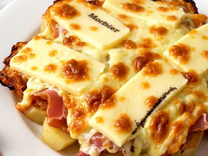 A top-down view of a slow cooker filled with layers of potatoes, bacon, and slices of Morbier cheese.