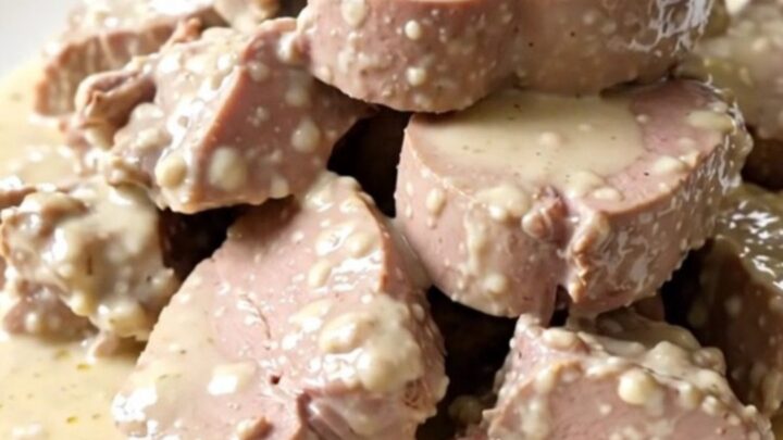 A top-down view of a slow cooker filled with raw veal, leeks, mushrooms, and carrots on a speckled countertop.