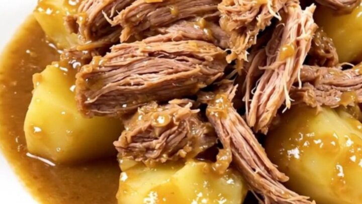 A rustic slow cooker pork roast served with melting potatoes on a white plate.
