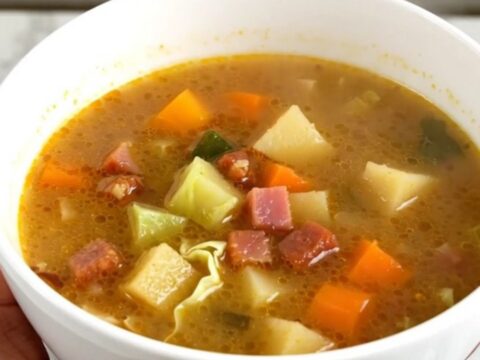 Bol de soupe fumante au chou et lardons sur un plan de travail en quartz moucheté.