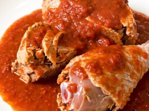 Close-up of slow cooker turkey osso buco served on a white plate with glossy tomato sauce.