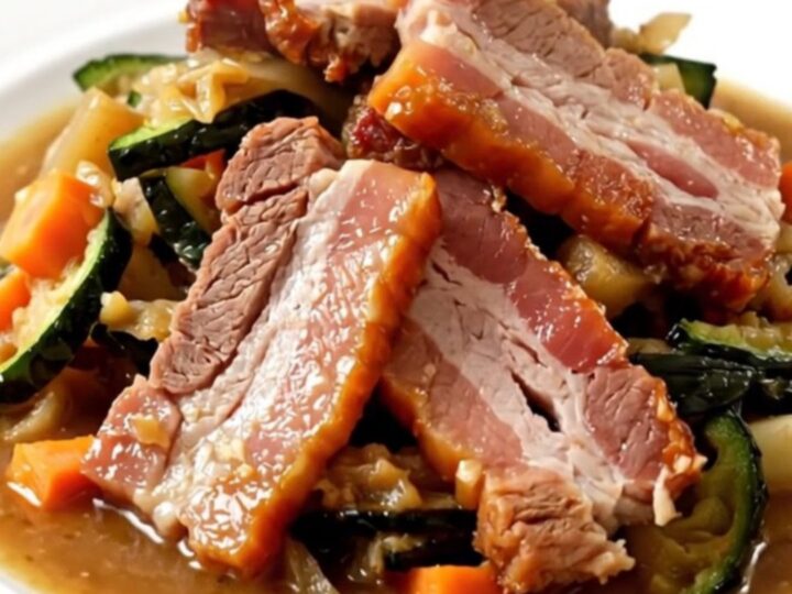 A steaming bowl of slow cooker hotpot featuring sliced sausages, smoked bacon