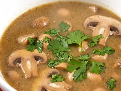 Bol de soupe aux champignons fumante et onctueuse garnie de persil frais sur un fond de cuisine clair.