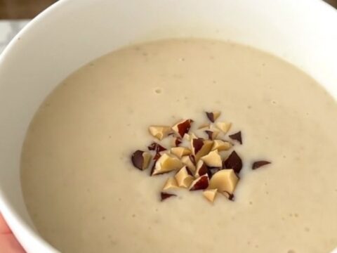 A steaming bowl of creamy, light-colored celeriac and chestnut soup garnished with chestnut pieces.
