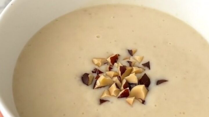 A steaming bowl of creamy, light-colored celeriac and chestnut soup garnished with chestnut pieces.