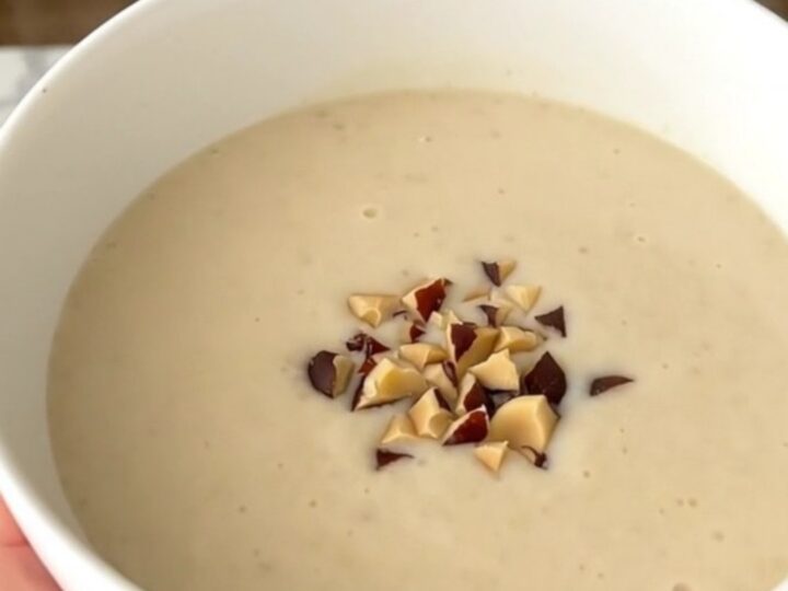 A steaming bowl of creamy, light-colored celeriac and chestnut soup garnished with chestnut pieces.