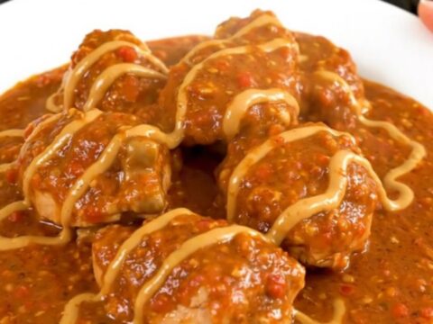 A steaming bowl of chicken mafé in a slow cooker, showcasing tender chicken and carrots in a rich peanut-tomato sauce.