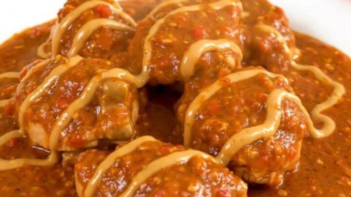 A steaming bowl of chicken mafé in a slow cooker, showcasing tender chicken and carrots in a rich peanut-tomato sauce.
