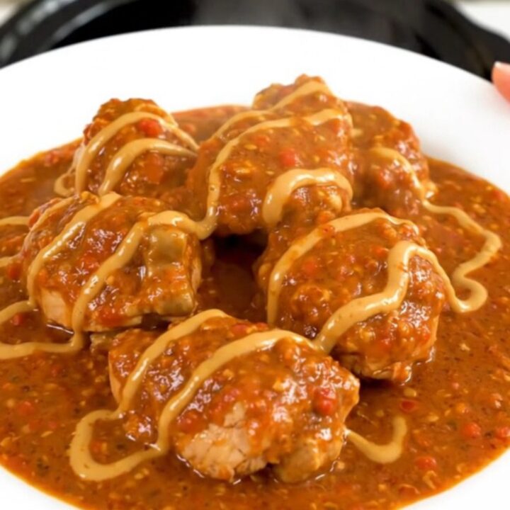 A steaming bowl of chicken mafé in a slow cooker, showcasing tender chicken and carrots in a rich peanut-tomato sauce.