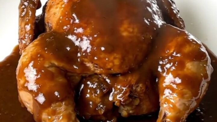 A close-up shot of slow-cooked chicken legs with a glossy beer gravy on a white plate.