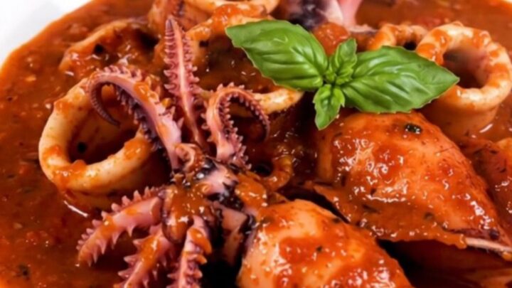 A top-down view of raw cuttlefish, sliced onions, garlic, and tomato sauce in a slow cooker insert.