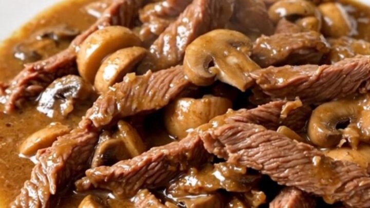 Vue de dessus d'un bœuf Stroganoff crémeux servi dans une assiette blanche, avec une sauce brillante.